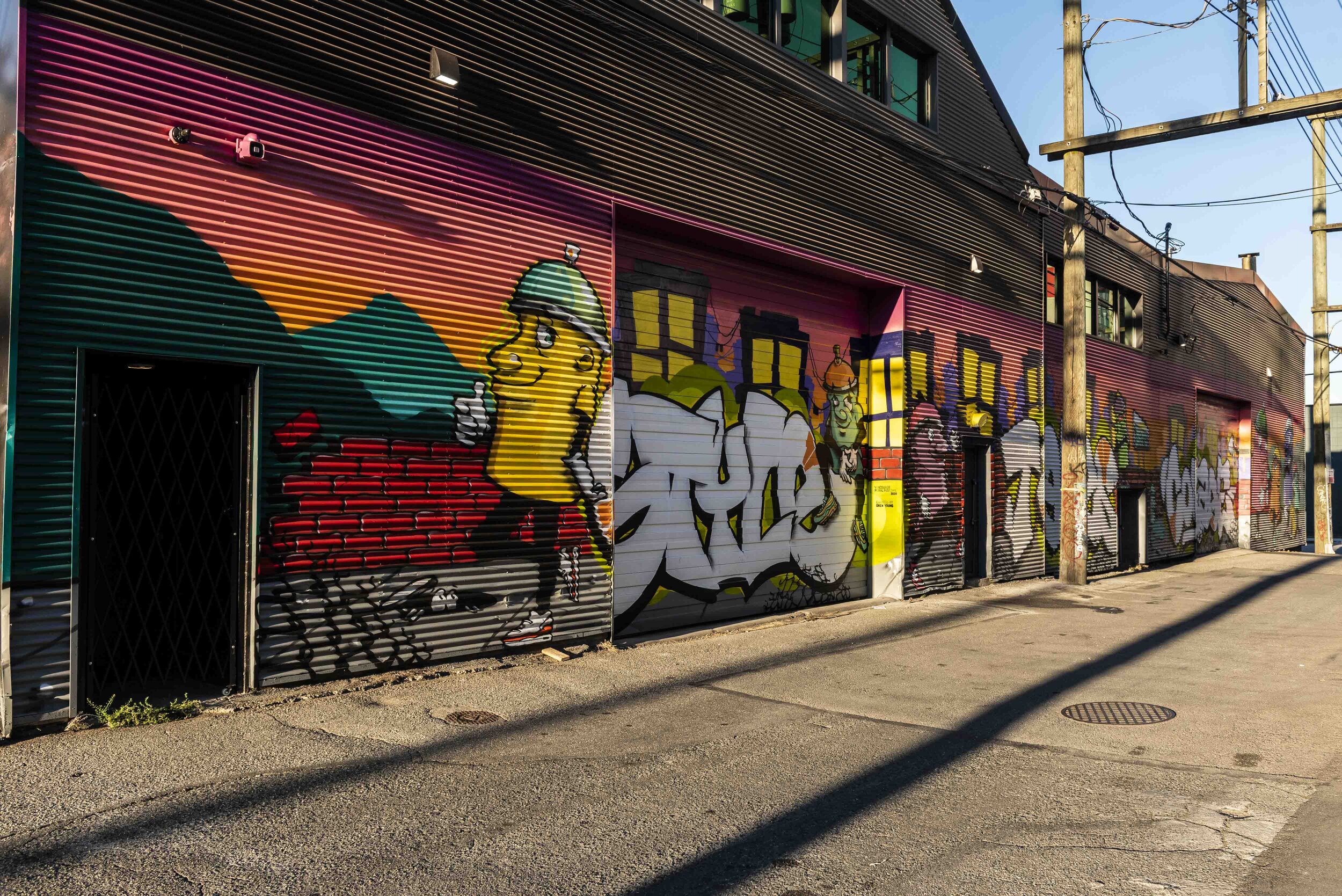 Graffiti style mural with spray can characters and big stylistic lettering.