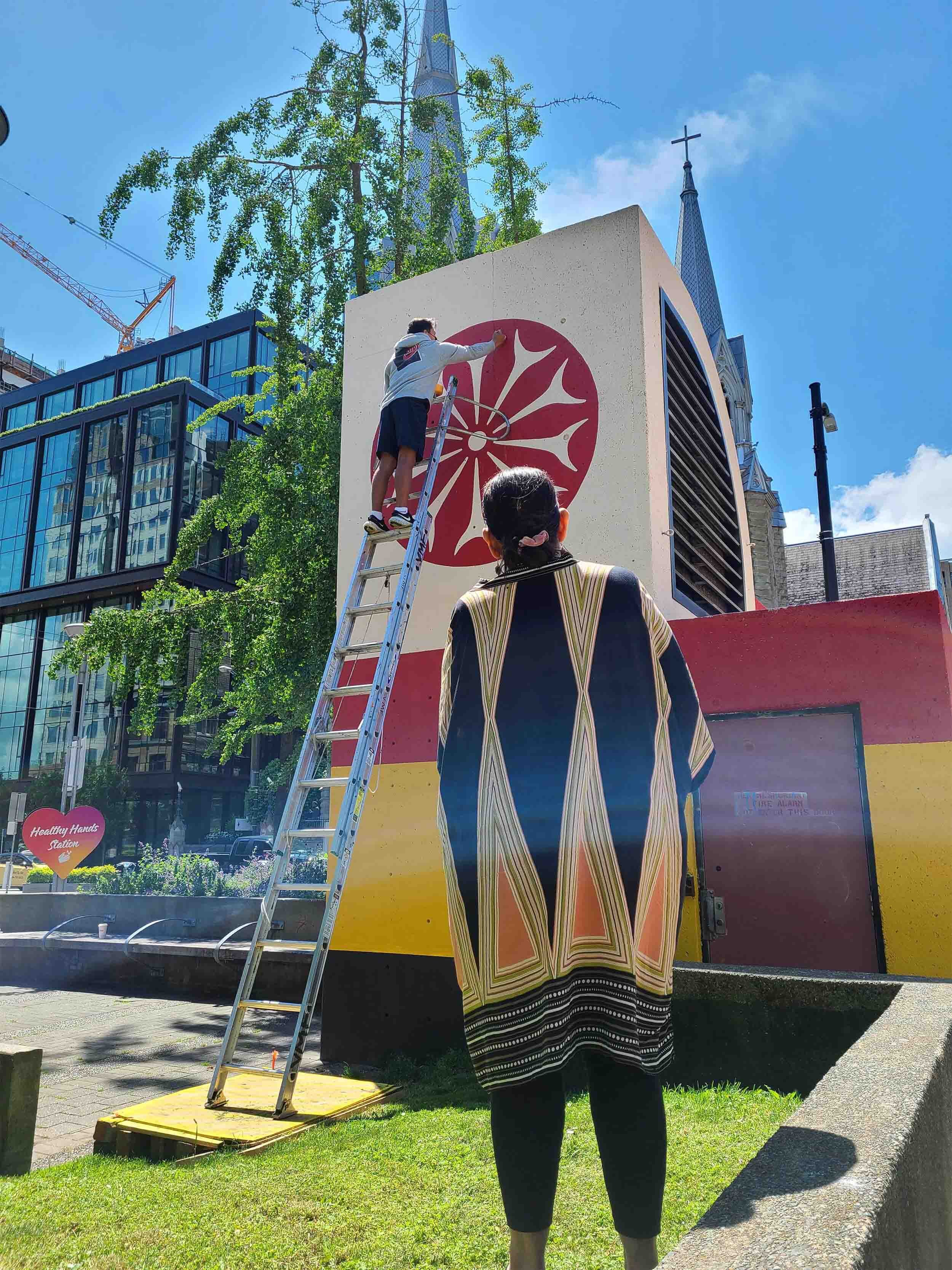 Blanketing The City IV Cathedral Square - Debra Sparrow & grandson painting spindle whorl dots.jpg